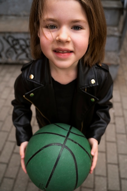 Free photo smiley girl holding ball high angle