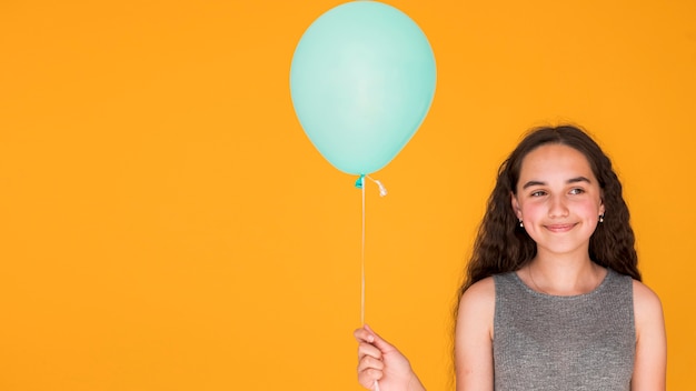 Smiley girl holding a blue balloon with copy space