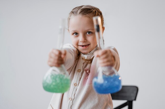 Smiley girl holding chemical elements in recipients