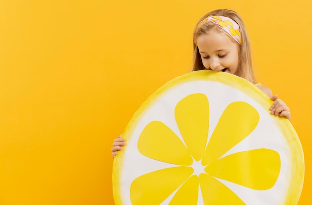 Free photo smiley girl holding lemon slice decoration