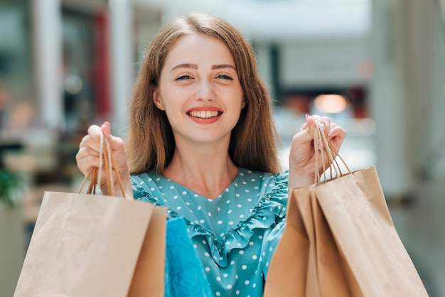 Foto gratuita ragazza sorridente che tiene i sacchetti della spesa