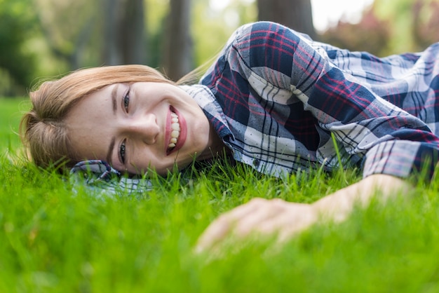 잔디에 머물고있는 동안 카메라를보고 웃는 소녀