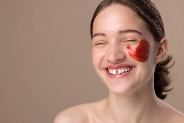 Foto gratuita ragazza sorridente che posa con la vista laterale della benda sull'occhio