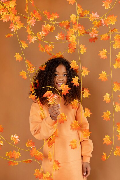 Foto gratuita ragazza di smiley che posa con le foglie