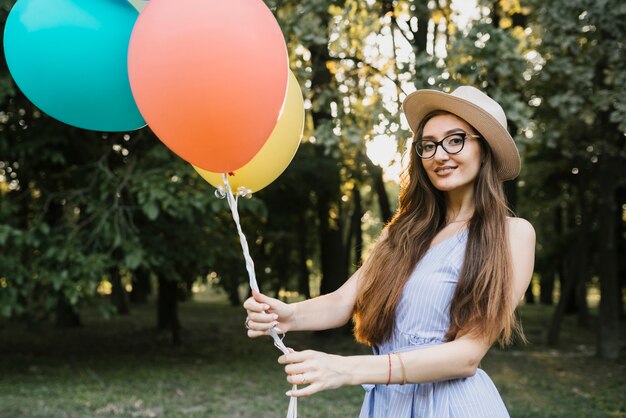 Улыбающаяся девушка с воздушными шарами смотрит в камеру