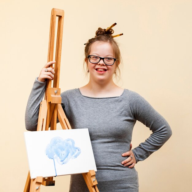 Smiley girl with down syndrome posing with easel