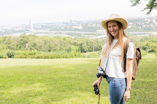 Foto gratuita ragazza sorridente con fotocamera dslr