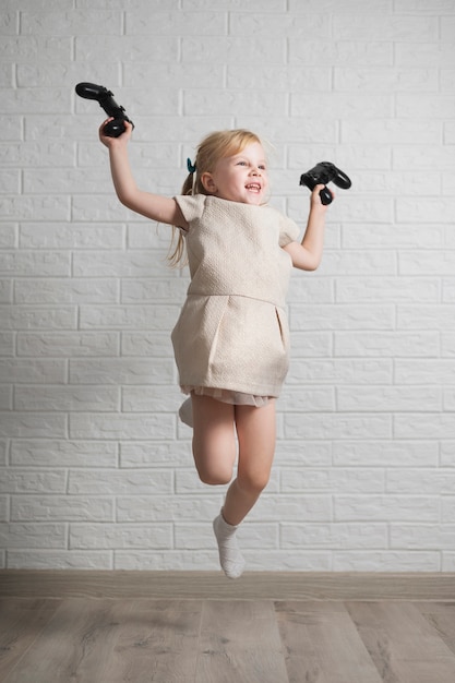 Free photo smiley girl with joysticks in hand jumping