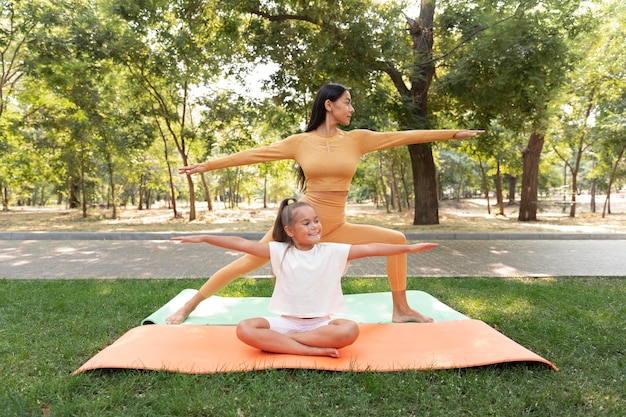 Smiley girl and woman doing yoga full shot