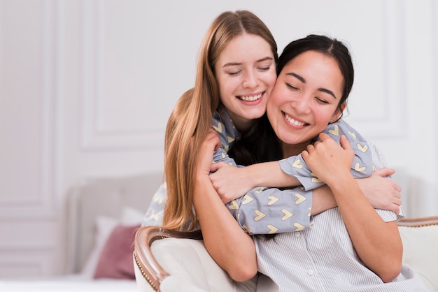 Smiley girlfriends at home hugging