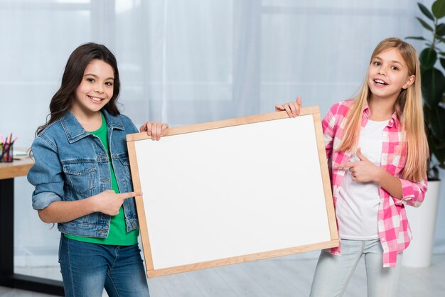 Free photo smiley girls holding frame