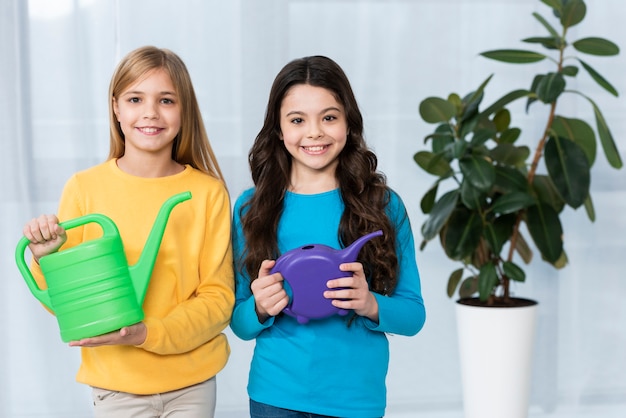 Free photo smiley girls watering flowers