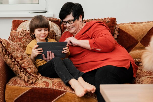 Smiley grandmother playing with grandson on tablet