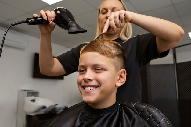 Smiley kid getting hair styled at salon