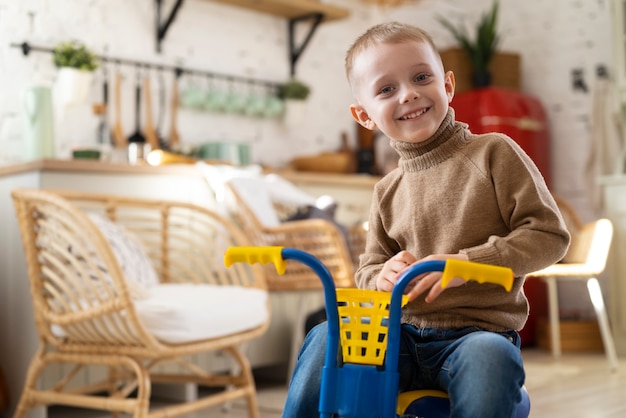 Free photo smiley kid with tricycle indoors medium shot