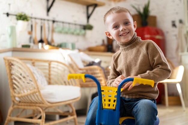 Smiley kid with tricycle indoors medium shot