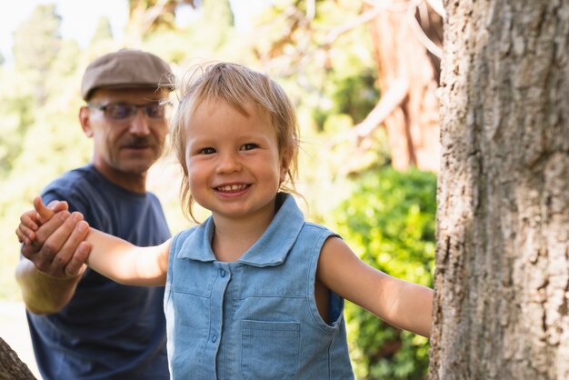 Смайлик маленький мальчик исследует деревья с дедушкой