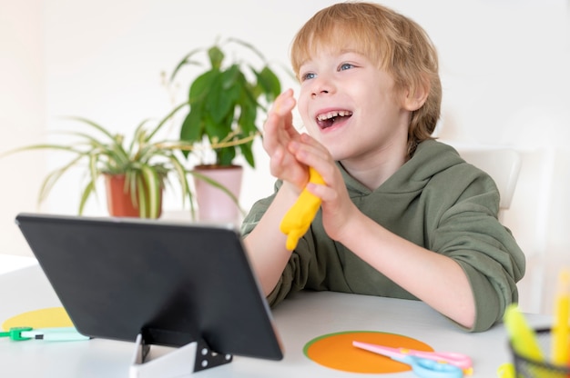 Foto gratuita ragazzino di smiley facendo uso della compressa a casa