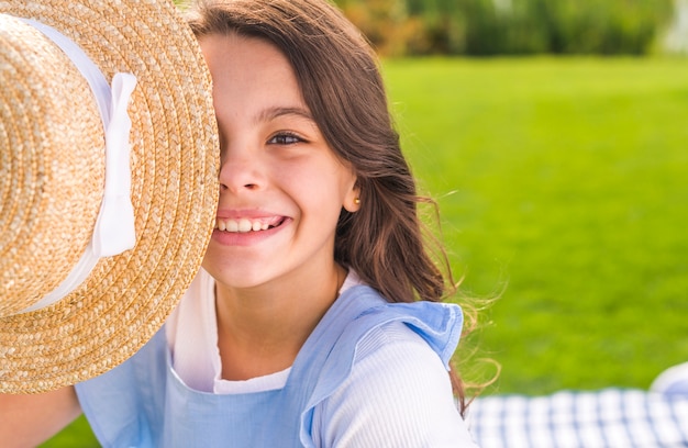 Smiley little girl covering her eye with a straw hat