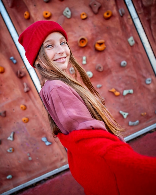 Smiley little girl posing next to a climbing wall