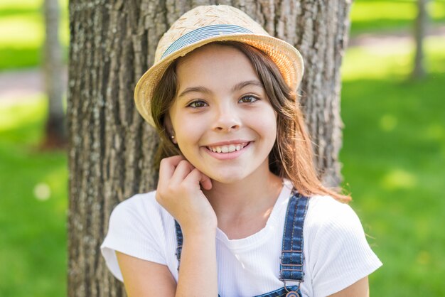 웃는 어린 소녀는 나무 앞에서 포즈
