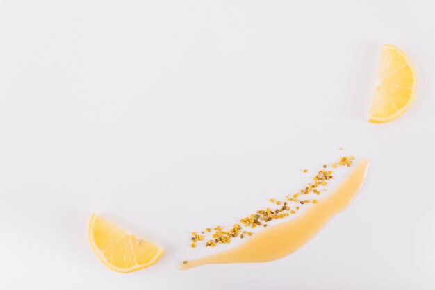 Smiley made with honey; bee pollen and lemon on white background