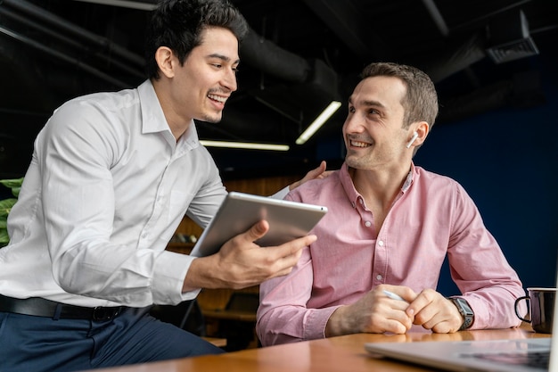 Free photo smiley male coworkers conversing at work