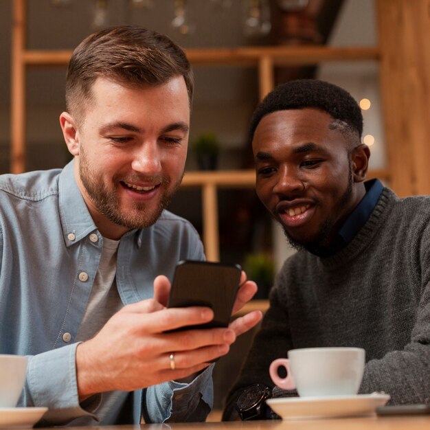 Smiley male friends looking on mobile