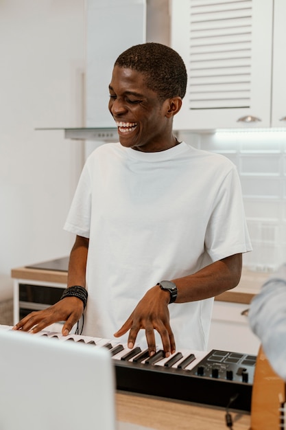 Smiley male musician at home playing electric keyboard