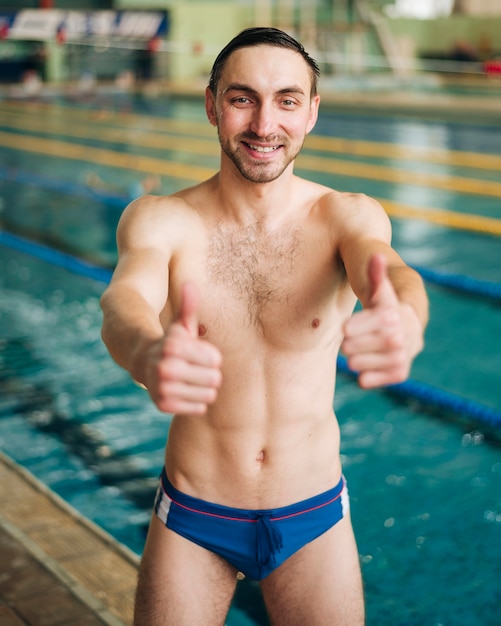 무료 사진 확인 표시를 보여주는 스마일 남성 수영