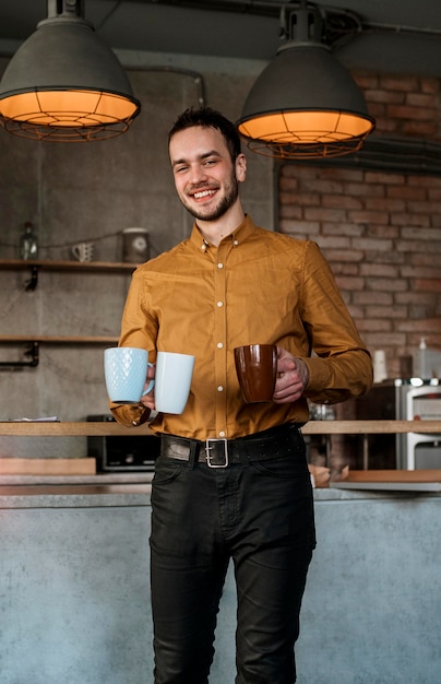 smiley man carrying mugs with coffee