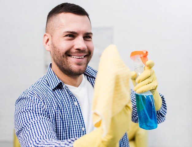 Smiley man cleaning while using rag