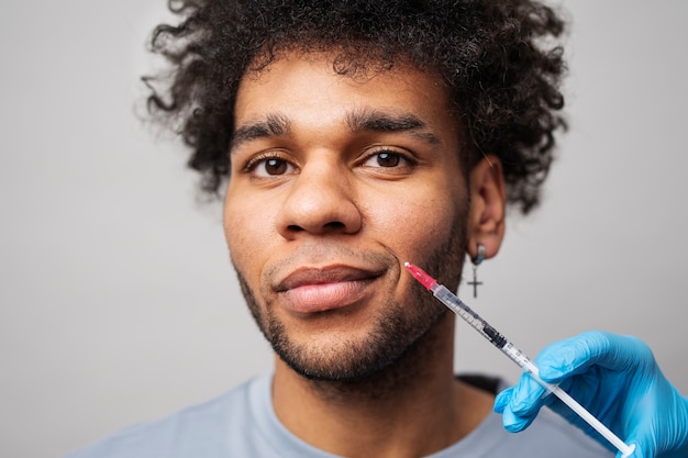 Free photo smiley man getting hyaluronic acid injection