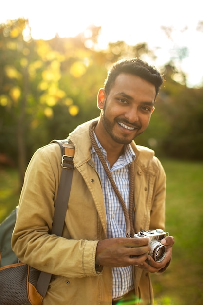 Foto gratuita uomo sorridente che tiene la fotocamera a scatto medio