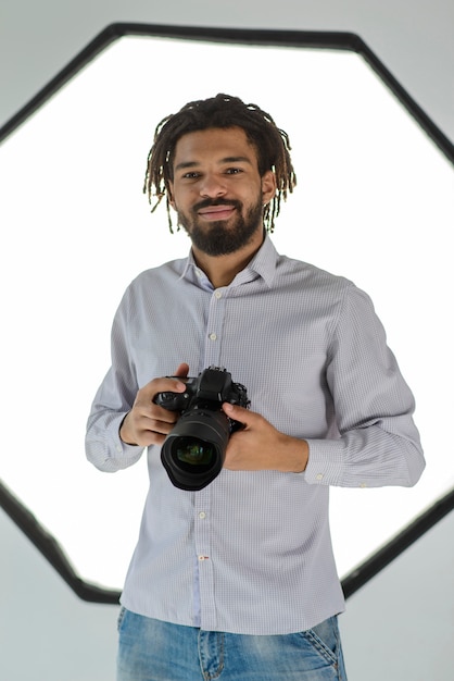 Free photo smiley man holding camera