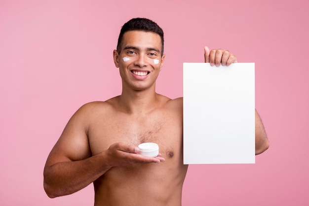 Smiley man holding face cream and blank placard