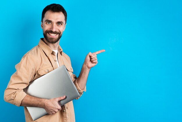 Smiley man holding laptop and pointing