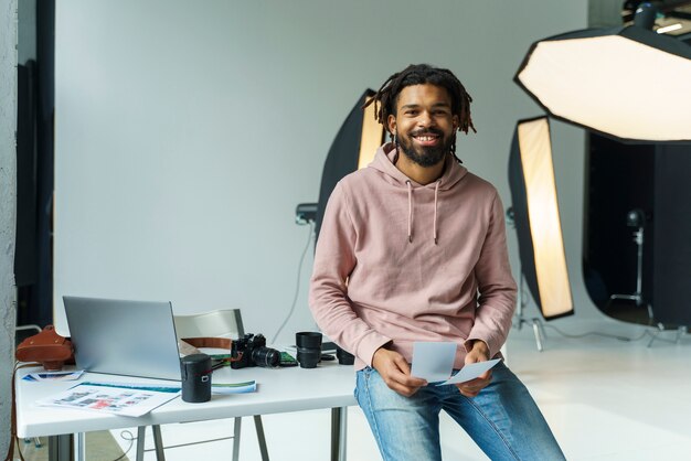 Free photo smiley man holding photos indoors