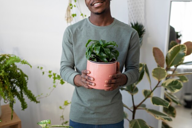 Smiley man holding plant at home front view