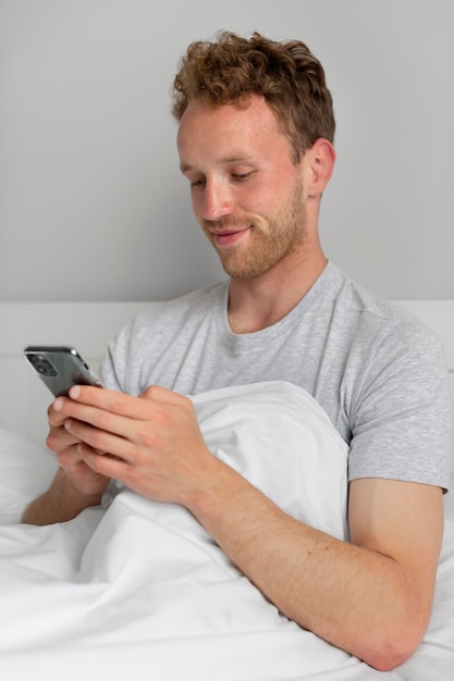 Smiley man holding smartphone medium shot