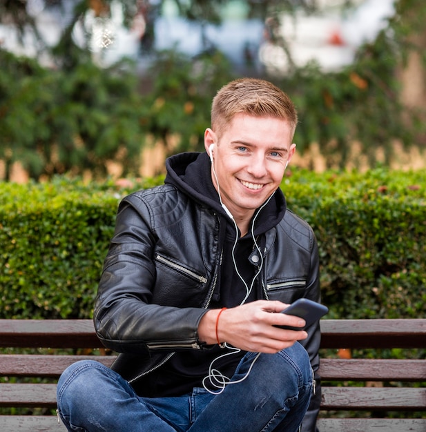 Foto gratuita uomo di smiley che ascolta la musica sulle cuffie