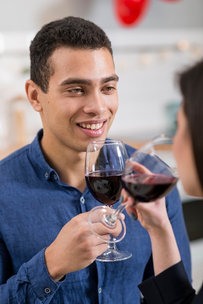Smiley man looking at his girlfriend while holding a glass of wine