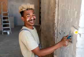 Free photo smiley man painting the walls of his new home