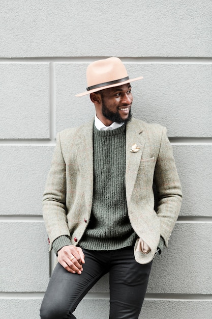 Free photo smiley man posing on a grey wall