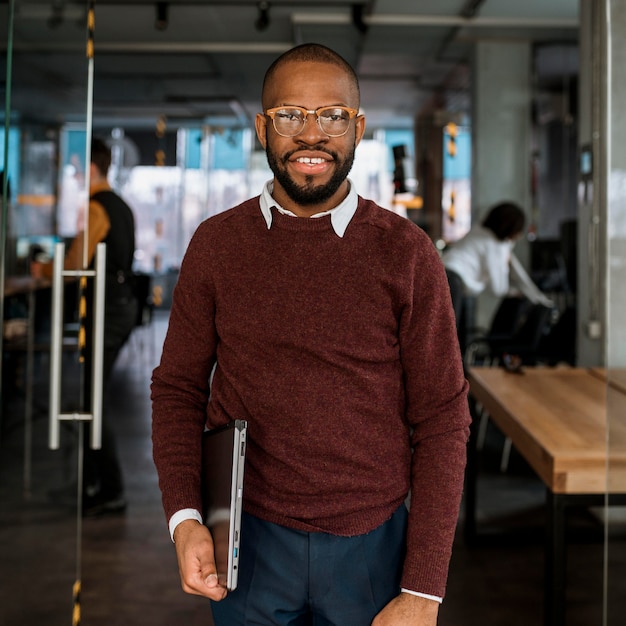 Smiley man posing while holding a laptop