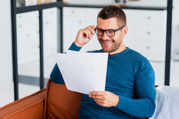 Free photo smiley man reading at home documents