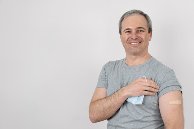 Free photo smiley man showing bandage on arm after vaccination