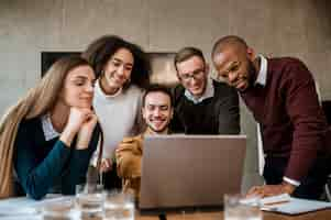 Free photo smiley man showing something to his colleagues on laptop during a meeting