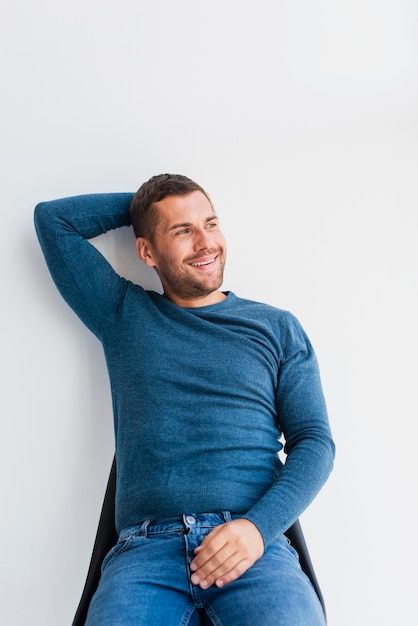 Free photo smiley man sitting on chiar at home