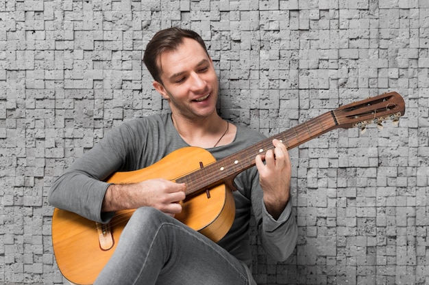 Free photo smiley man sitting on the floor and playing